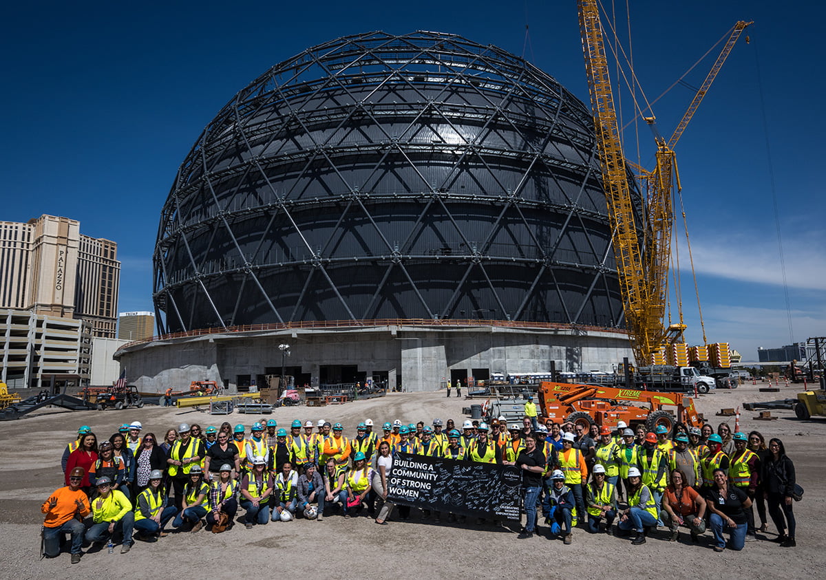 Women construction workers pose in front of project